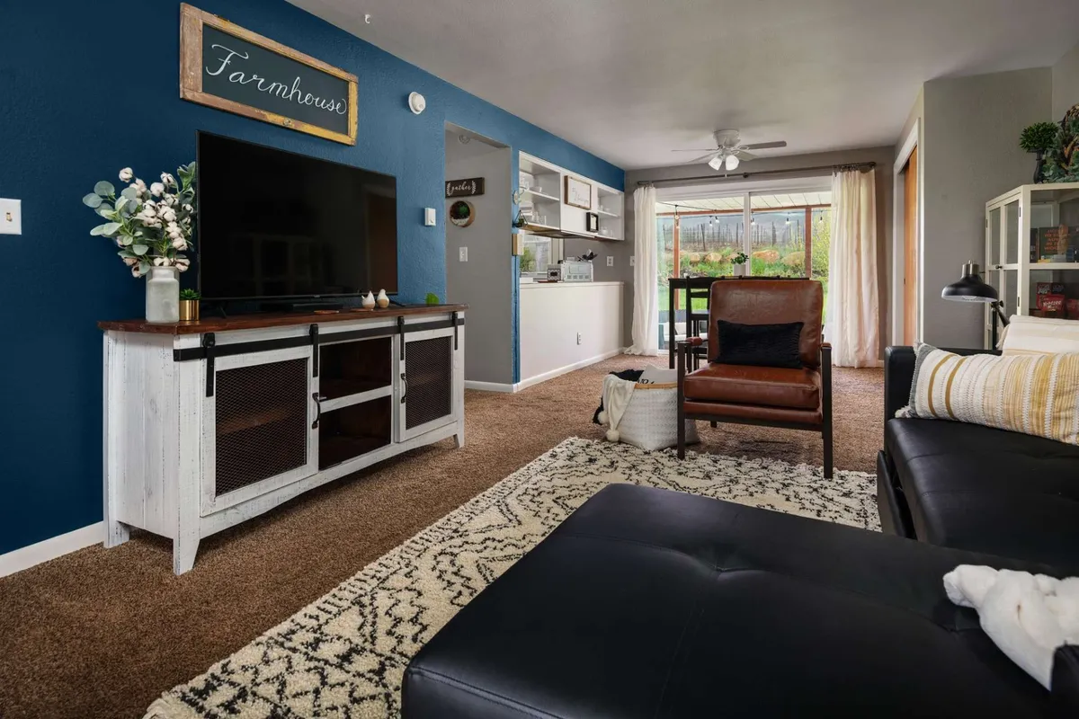 A welcoming living and dining space featuring a comfortable armchair, television, decorative sign, and a cozy dining area. The arrangement suggests a relaxed and homey atmosphere, perfect for unwinding with family or enjoying a movie night.