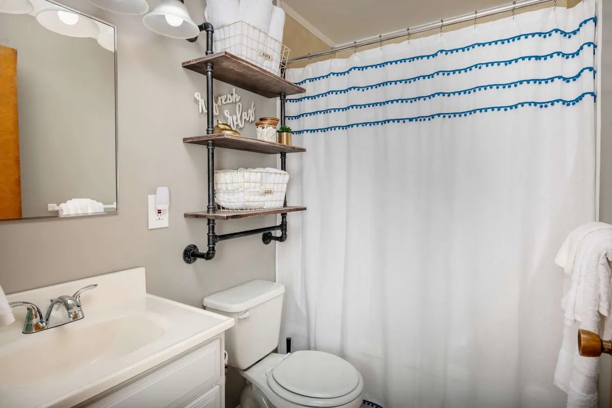 This bathroom scene features neatly arranged shelves with towels, stylish decorative items, a mirror, and a clean, modern sink. The space evokes a feeling of comfort, organization, and a spa-like ambiance that encourages relaxation and self-care.