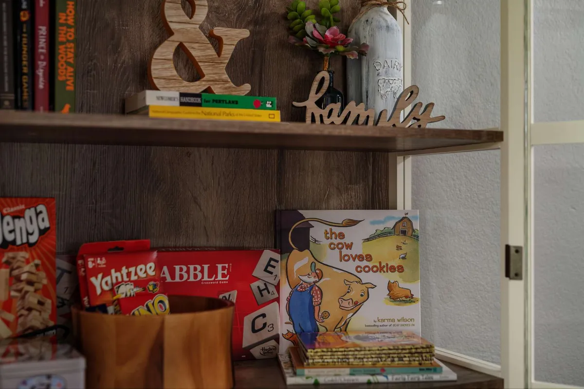 A cheerful corner with a 'family' sign, children's book, colorful board games, and a wooden ampersand, emphasizing togetherness and fun activities for guests of all ages.